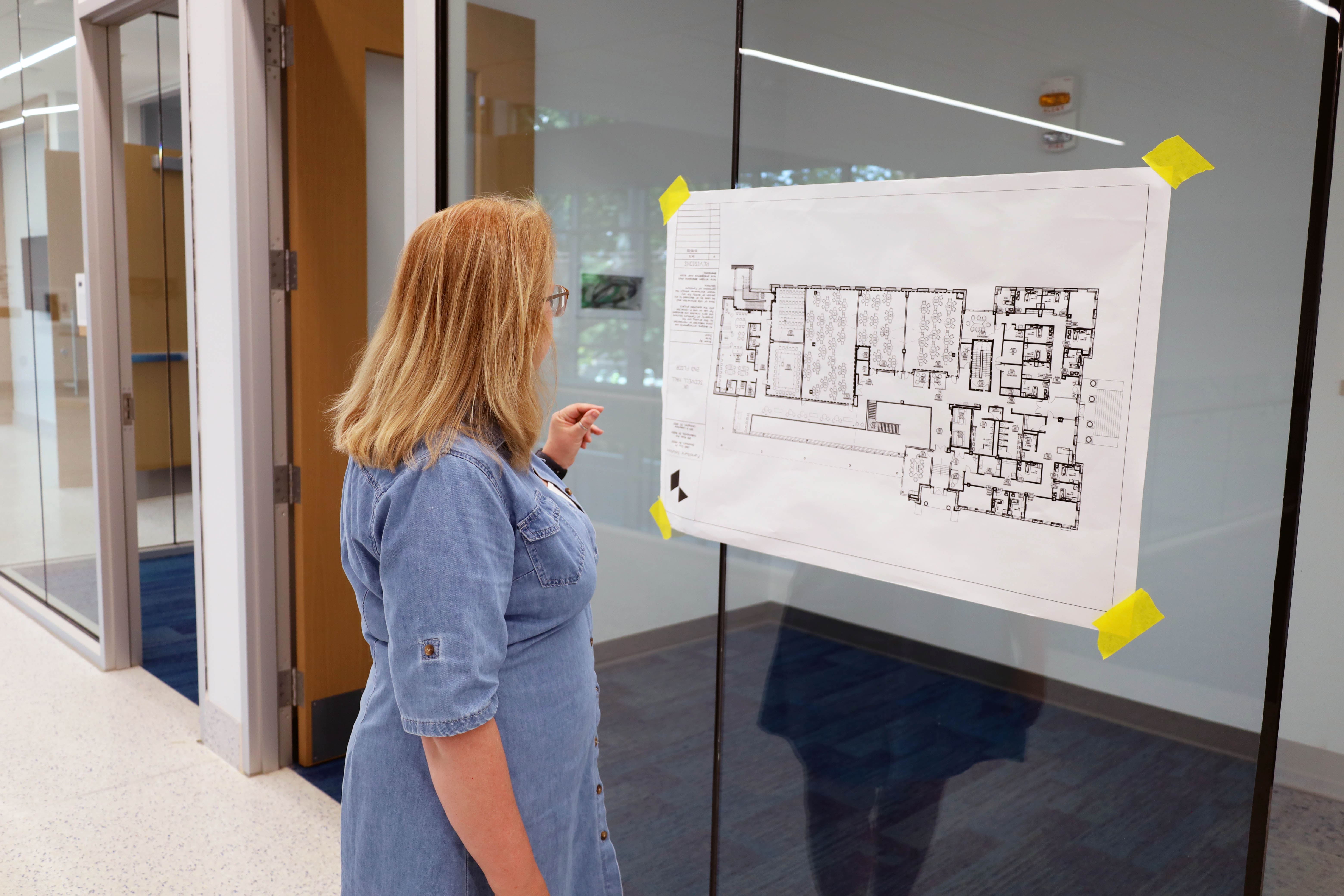 Sandy Redmon looking at a building diagram in a hallway at Scovell Hall