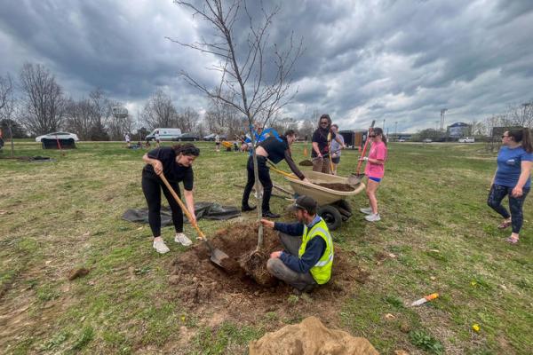 Nic Williamson assists students in planting trees