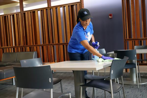  A custodial team member cleans a table