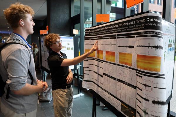 One student explains a research poster while one listens