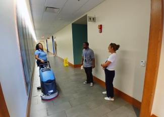 Woman cleans floor and talks to two other people