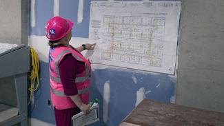 Women in construction hat and vest looking at construction plans