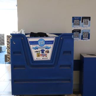 A large blue container for Give & Go Donations. The container has a sign of accepted donations.
