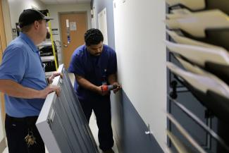  Maintenance technicians install new display cases on the wall