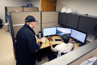 Two maintenance technicians in a cubicle looking up a part on the computer