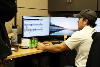 A facilities maintenance supervisor sitting at a desk looking at computer screen