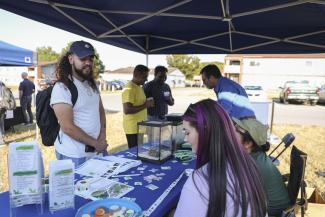 People standing at a booth outside talking