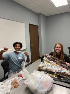 Two students making a mat out of plastic bags