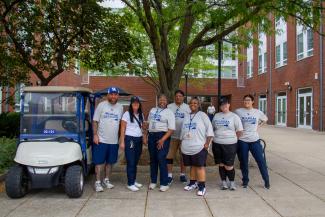 FM employees posed by a golf cart during move-in