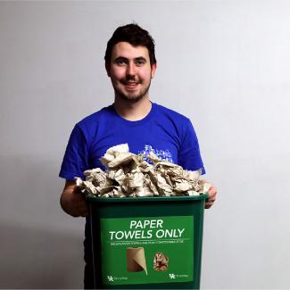 Shaun Laving holding a brown paper towels only collection bin.