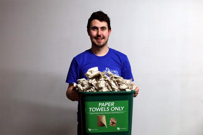 A person holding a bin full of brown paper towels