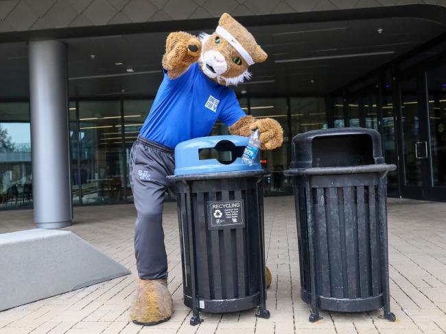 UK's Wildcat recycling a plastic bottle outside the Gatton Student Center.