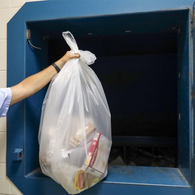 A clear bag being added to the compactor 