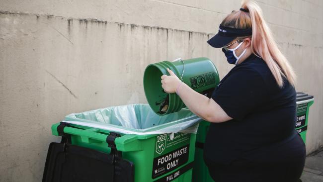 UK Dining employee dumping coffee beans into compost containers. 