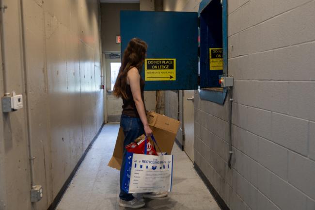 UK student throwing away her recyclables in the compactor.