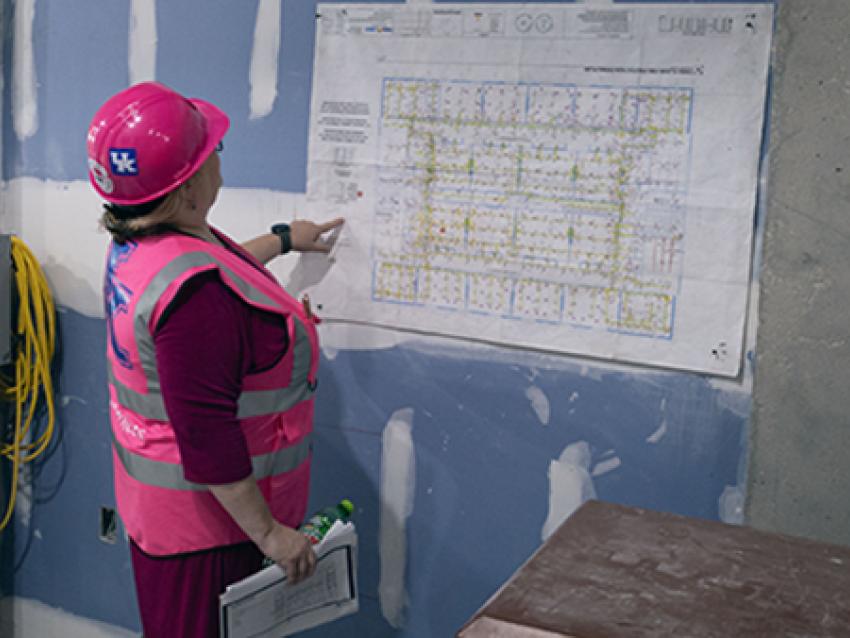 Women in construction hat and vest looking at construction plans