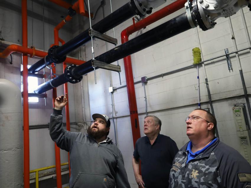 Three people stand in the Central Utility Plant looking at the integration of the rental deaerator tank