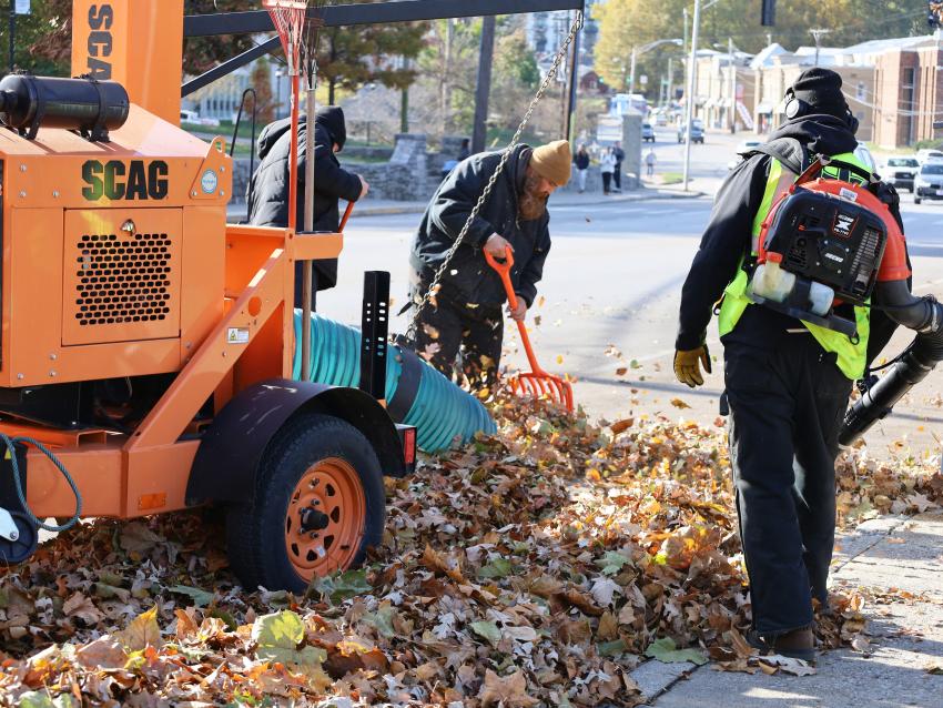 Grounds employees collect leaves on campus with a leaf blower and vacuum